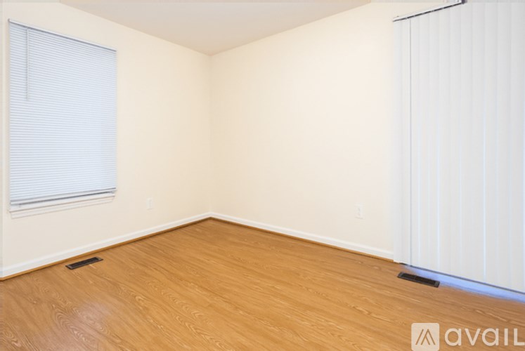 A room with wooden flooring and a window with blinds.