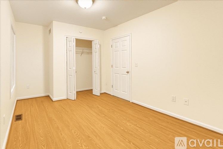 A room with wooden floors and white walls, with a door and a mirror.