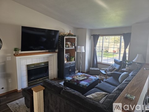A living room with a fireplace and a television on the wall.