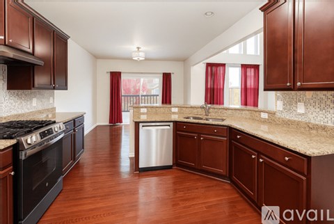 A kitchen with dark wood cabinets and a stainless steel dishwasher.