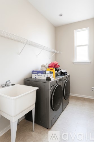 A white sink is in a laundry room with a washer and dryer.