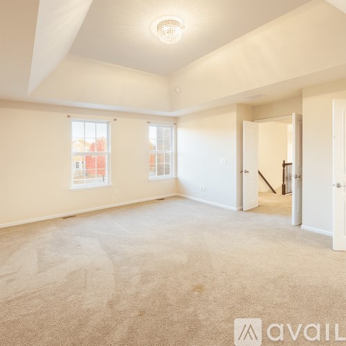 A spacious room with a carpeted floor and white walls.