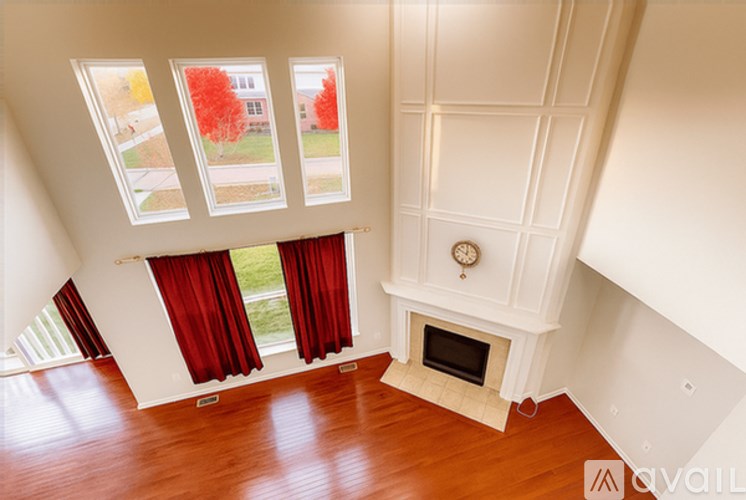 A large empty room with a fireplace and a window overlooking a tree.