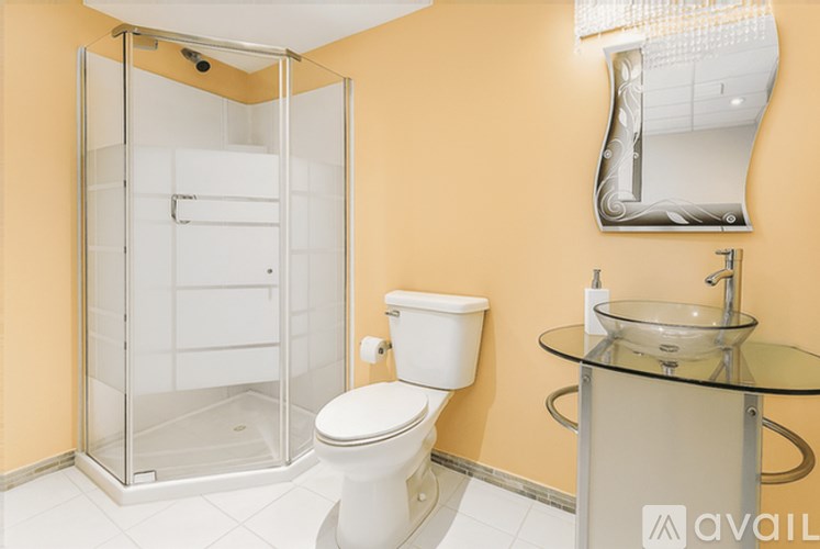 A bathroom with a toilet, a glass table, and a shower with a glass door.