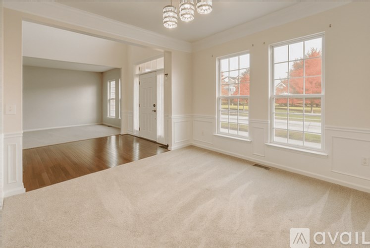 A spacious room with a carpeted floor and a chandelier hanging from the ceiling.