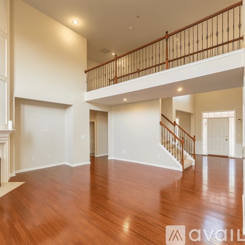 A spacious living room with hardwood floors and a staircase leading to the upper level.