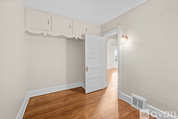 A room with a white door and wooden floor.