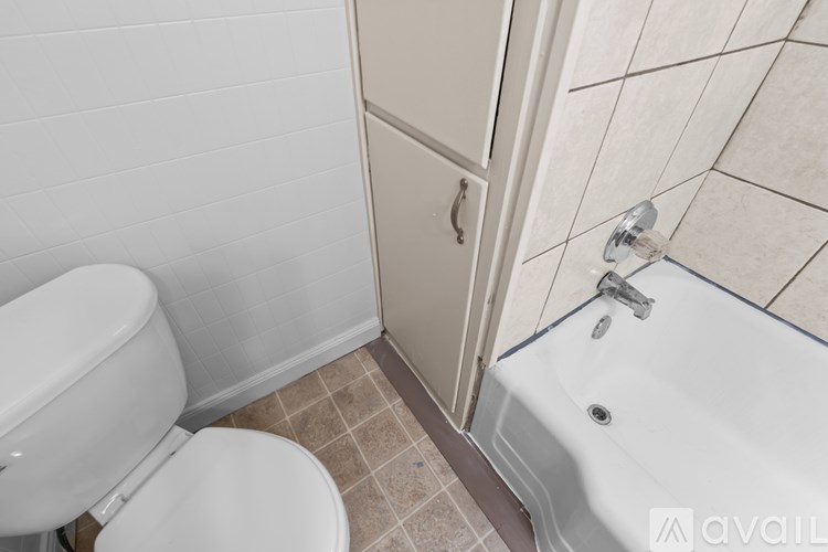 A white toilet sits next to a white bathtub in a bathroom.