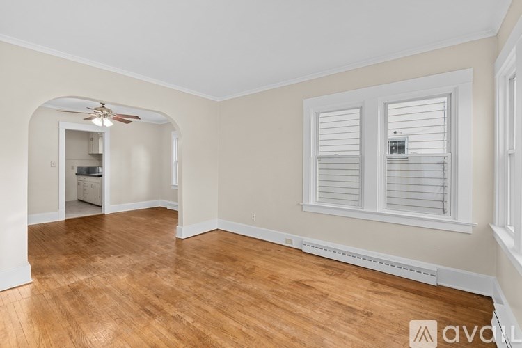 A room with wooden floors and white walls with a window and a fan.
