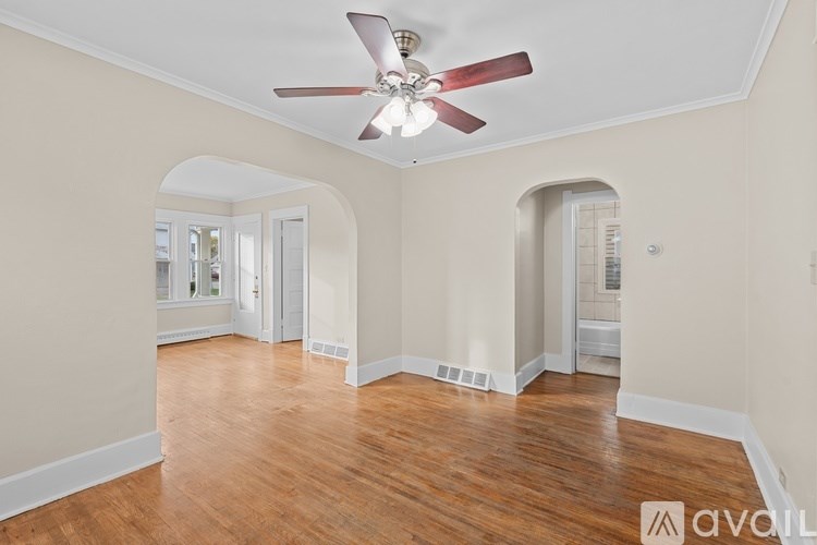 A room with a ceiling fan and wooden flooring.