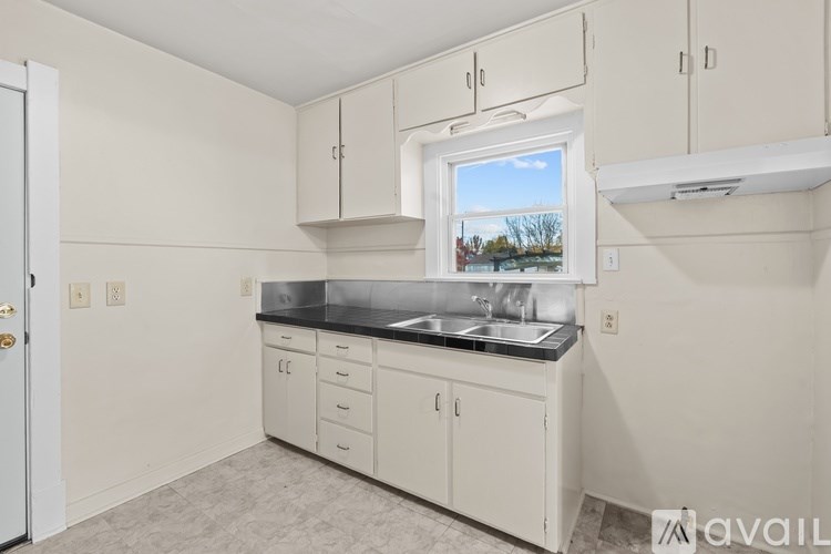 A kitchen with white cabinets and a window overlooking a field.