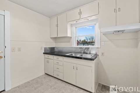 A kitchen with white cabinets and a window overlooking a field.