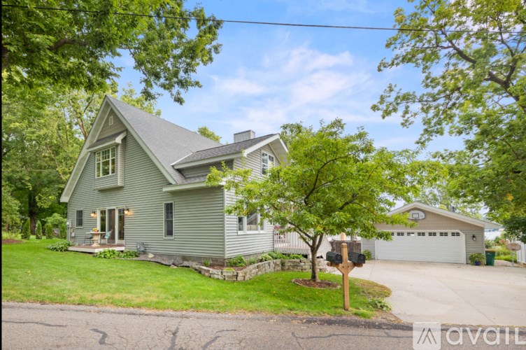 A house with a garage and a tree in front of it.