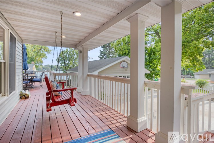 A red chair sits on a wooden porch.