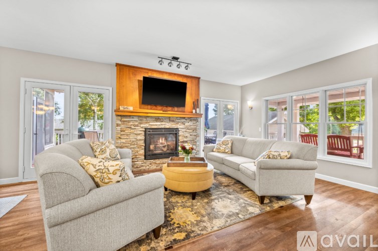A living room with a grey couch, a yellow coffee table, and a stone fireplace with a TV above it.