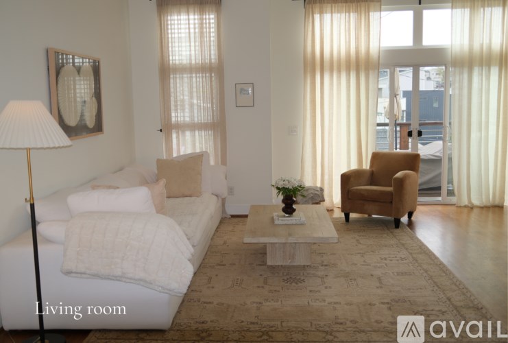 A living room with a white couch, a brown armchair, and a coffee table.