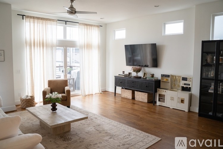 A living room with a brown chair, a wooden coffee table, and a flat screen TV mounted on the wall.