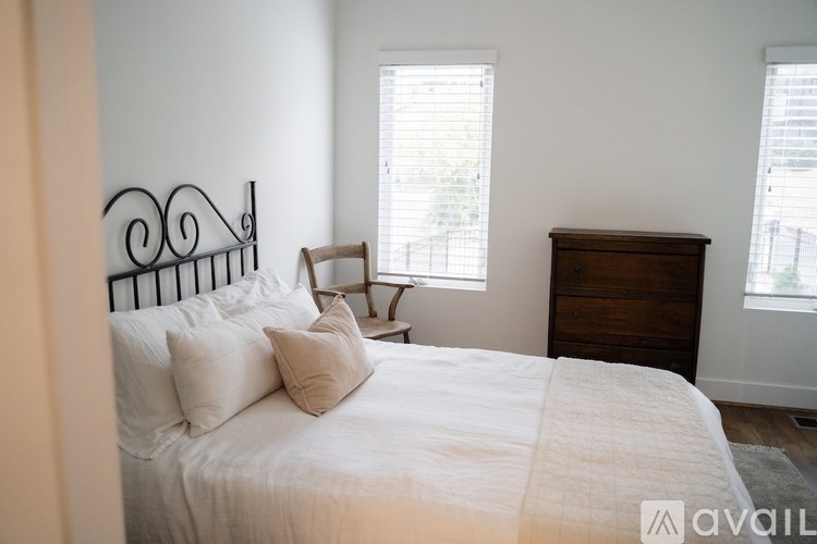 A bedroom with a white bed and a wooden dresser.