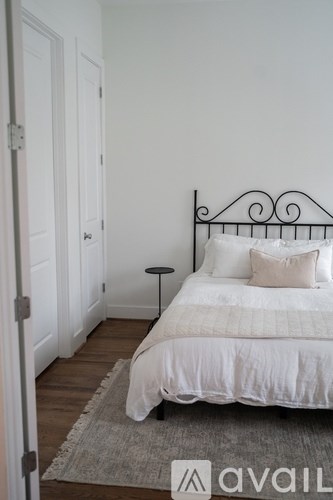 A white bed with a black metal headboard is in a room with white walls.