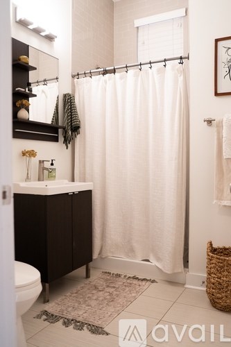 A bathroom with a white shower curtain and a brown rug.