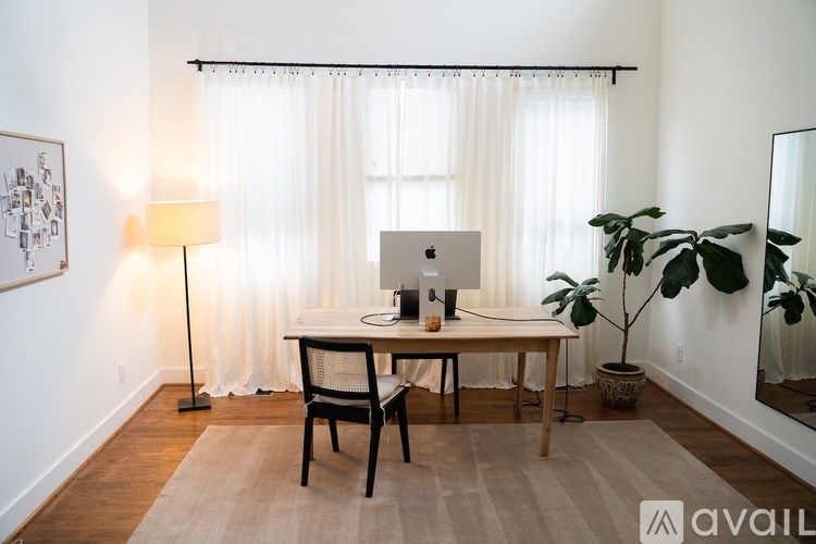 A room with a desk, chair, and a potted plant.