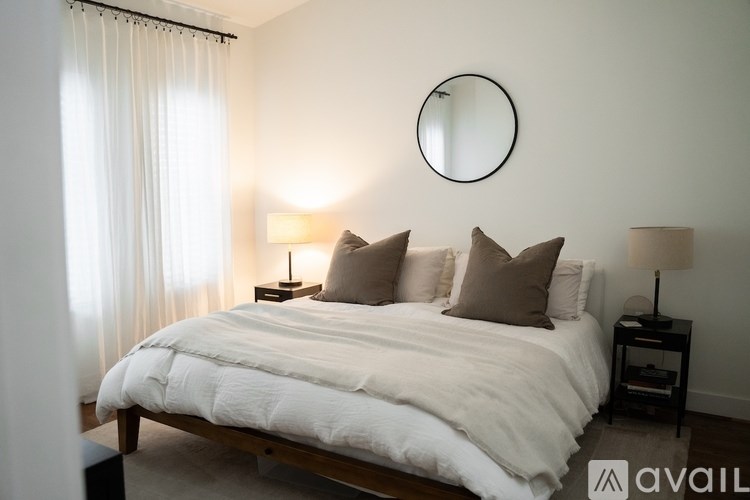 A bedroom with a large bed and two lamps.