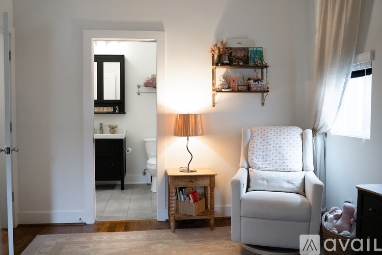 A white chair sits in a room with a small table and a lamp.
