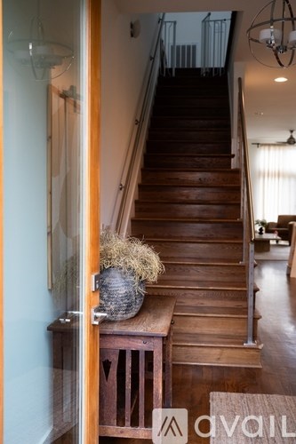 A wooden staircase with a glass railing and a round rug on the landing.