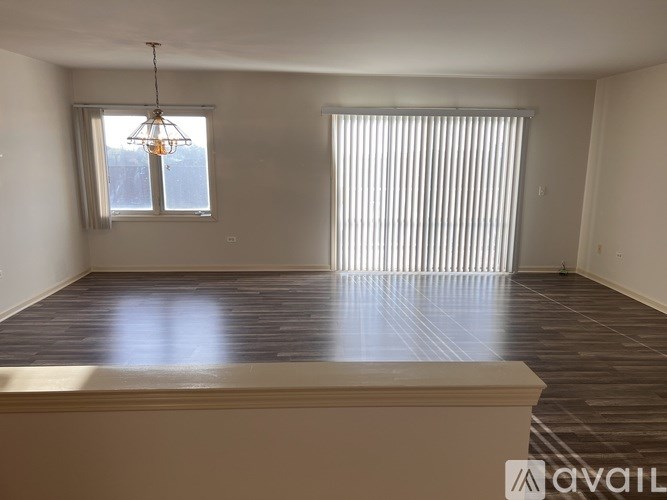A room with wooden floors and a large window with blinds.
