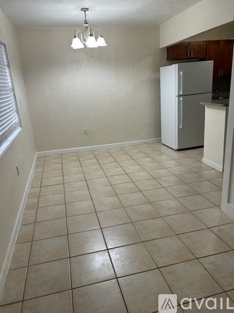 A kitchen area with a white refrigerator and tiled flooring.