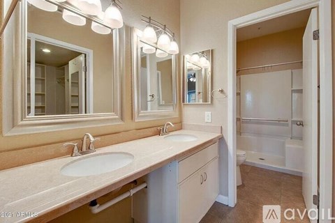A bathroom with a vanity, sink, mirror, and lighting fixtures.