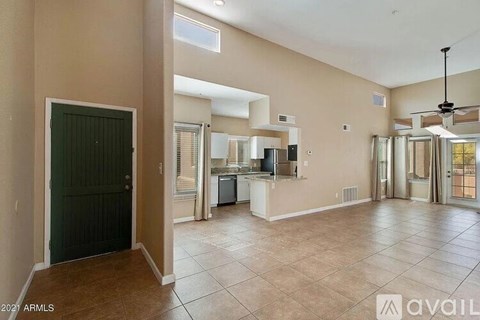 A spacious living room with a kitchen in the background.