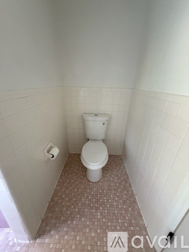A white toilet in a small bathroom with white walls and a tiled floor.