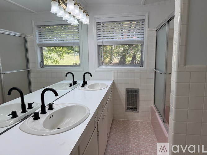 A bathroom with two sinks and a window with blinds.
