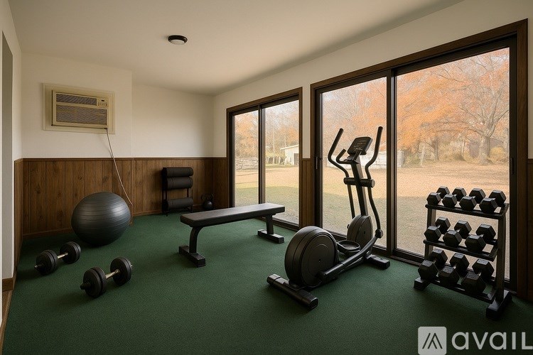 A gym room with a bench, dumbbells, a ball, and a treadmill.