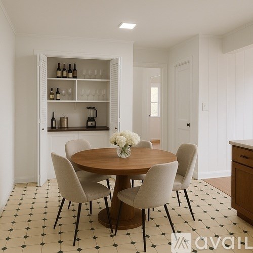 A dining room with a round wooden table surrounded by chairs and a wine rack in the background.