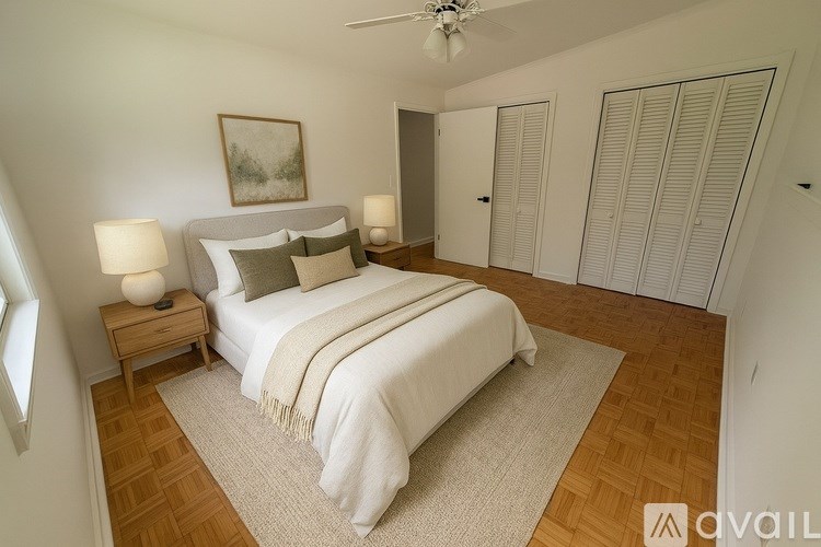 A bedroom with a large bed, a ceiling fan, and a painting on the wall.