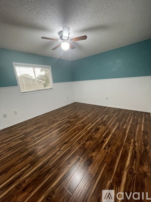 A room with wooden flooring and a ceiling fan.