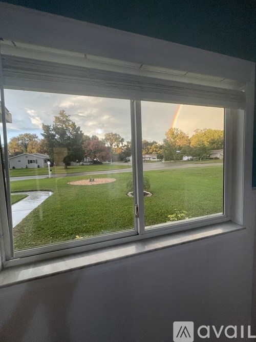 A window with a view of a green lawn and a house.