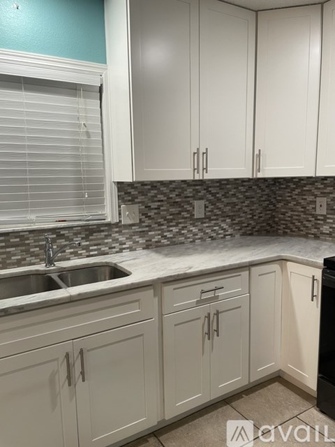 A kitchen with white cabinets and a black refrigerator.