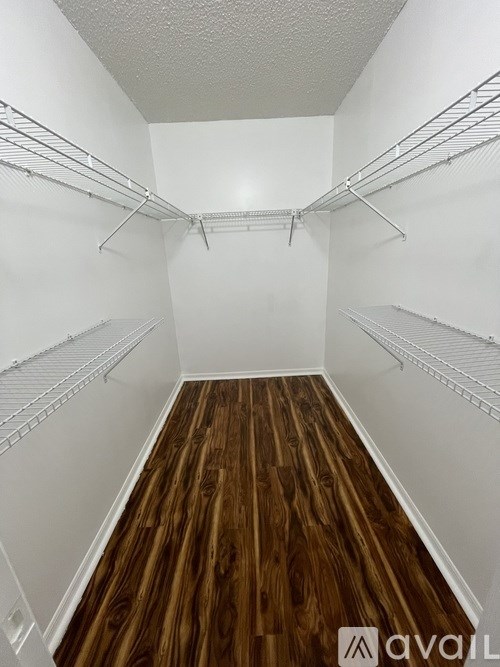 A walk-in closet with white shelves and wooden floors.