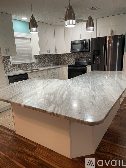 A kitchen with a marble countertop and stainless steel appliances.