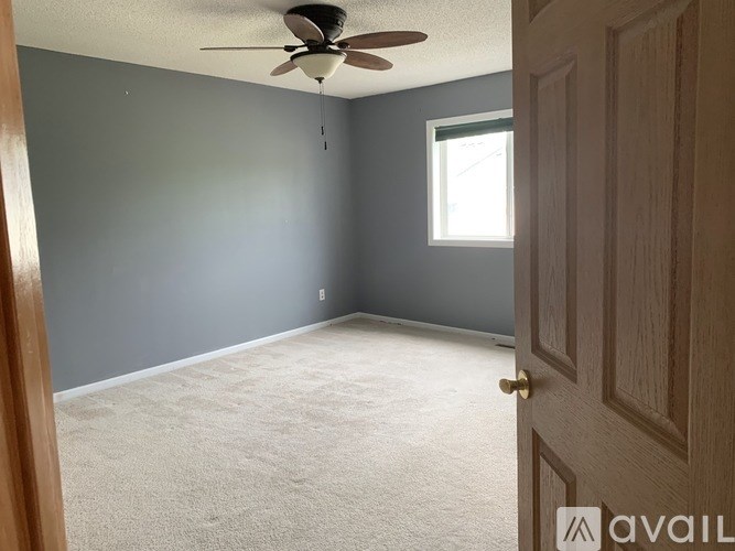 A room with a ceiling fan and a door.