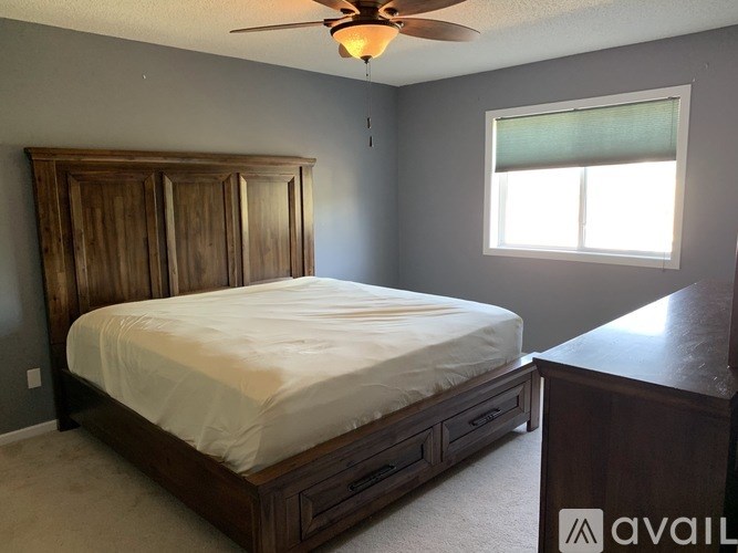 A bedroom with a large bed and a ceiling fan.