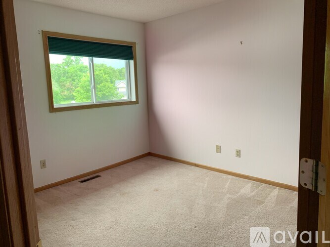 A room with a window and a carpeted floor.