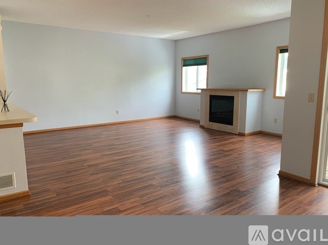 A spacious living room with wood flooring and a fireplace.