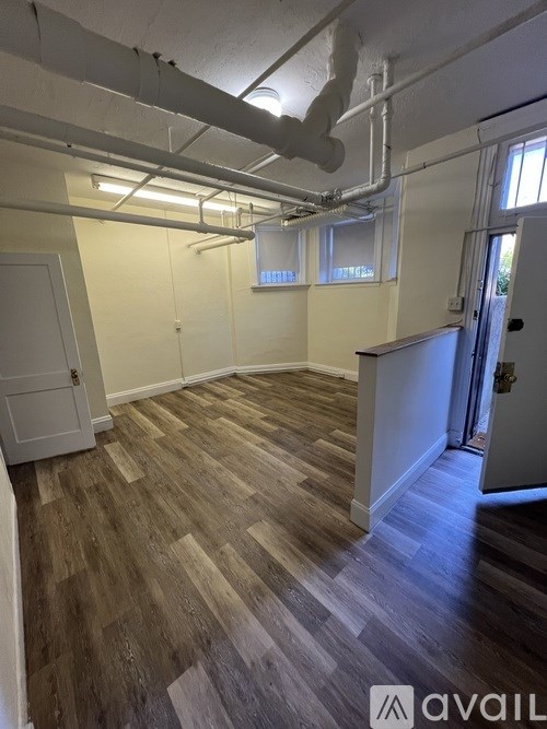 A room with wooden flooring and white walls.
