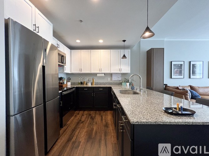 A modern kitchen with a stainless steel refrigerator and wooden floors.