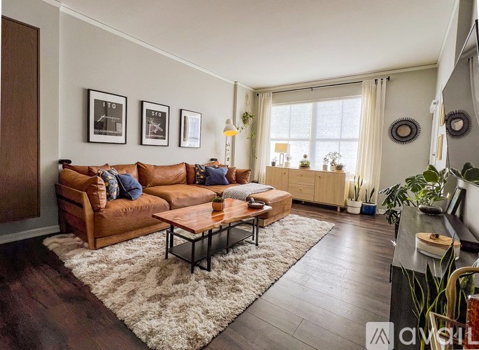 A living room with a brown sofa, a coffee table, and a rug.