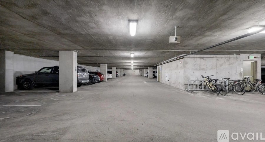 A parking garage with a few cars and bicycles.